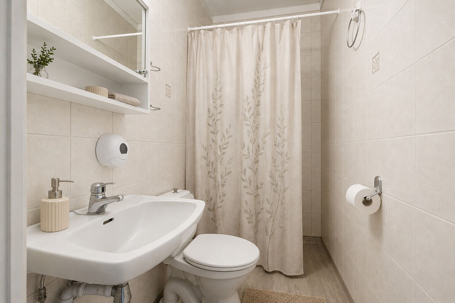 A bathroom with a white sink, toilet, and a shower curtain with a leaf pattern.