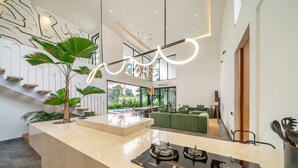 Une cuisine moderne dotée d’une cuisinière à gaz, d’un grand îlot central et d’un escalier au design minimaliste.