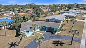 A residential area with houses, a swimming pool, and palm trees.