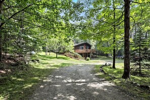 A cabin surrounded by trees with a gravel path leading to it.