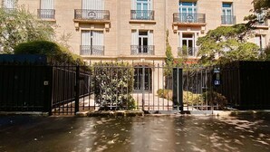 A multi-story building with balconies, a gated entrance, and a paved driveway. - Charming studio apartment in Neuilly – Jardin d'Acclimatation (Neuilly-sur-Seine)