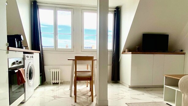 A modern apartment with a kitchen, a dining area, a TV, and a view of the sea. - Charming studio apartment in Neuilly – Jardin d'Acclimatation (Neuilly-sur-Seine)