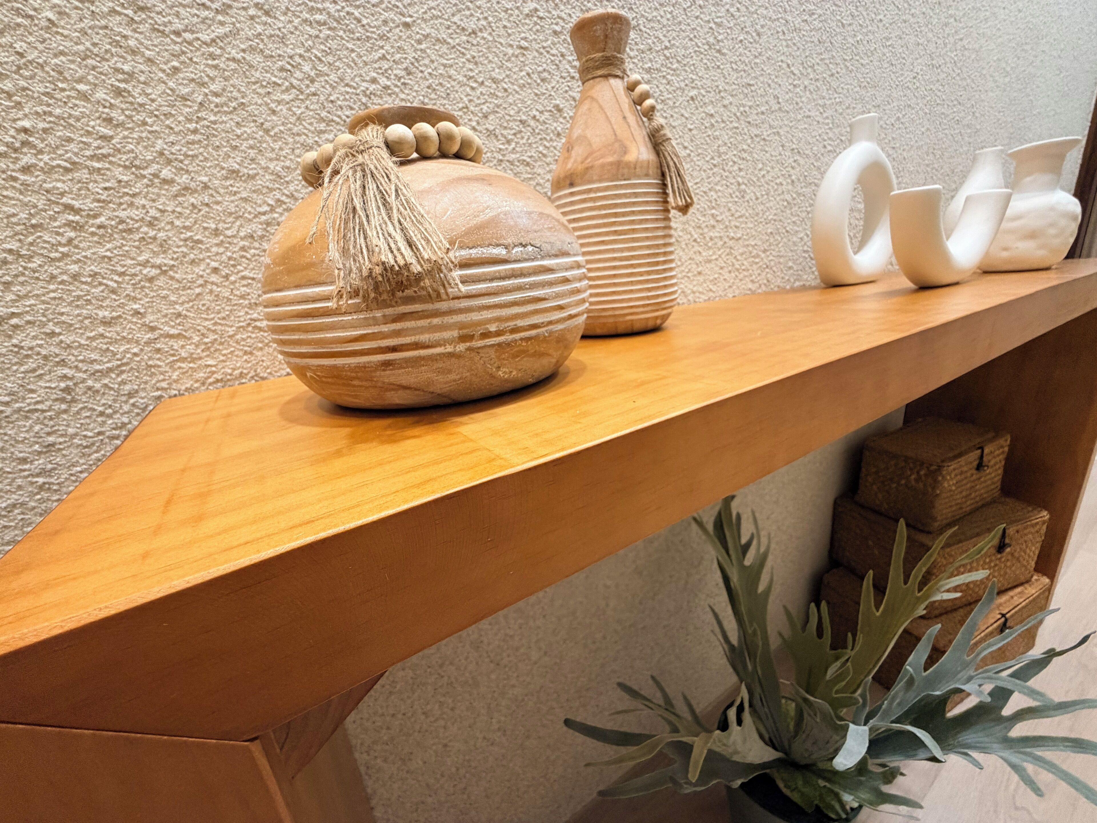 Un estante de madera con cerámica decorativa y una planta en maceta.