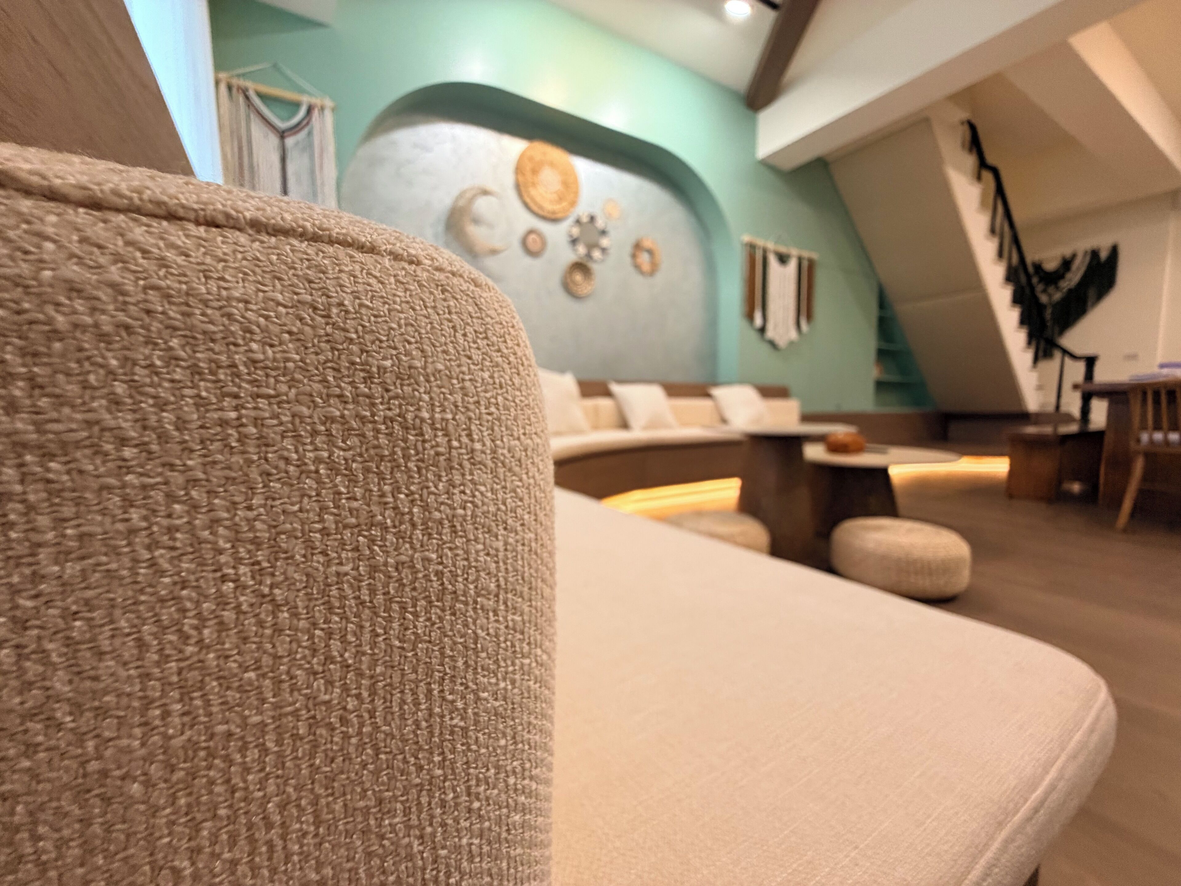 Un interior moderno con un sofá, una pared decorada y una escalera.