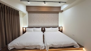 Una habitación de hotel moderna con una cama grande, cabecera de madera y una lámpara colgante.