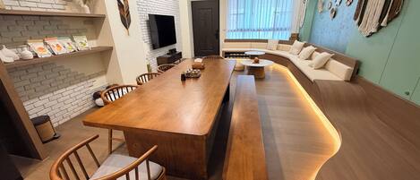 Una sala de estar moderna con una mesa de comedor de madera, un sofá y un televisor montado en la pared.