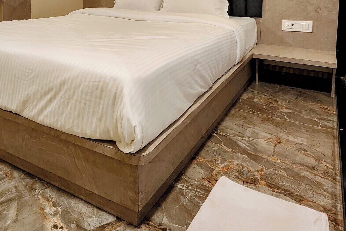 Ein Hotelzimmer mit einem großen Bett, einem Kopfteil, einem Nachttisch und zwei Pendelleuchten.