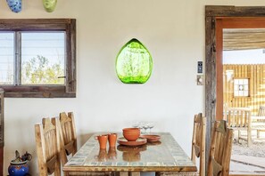 A dining area with a wooden table, chairs, and a green glass pendant light.