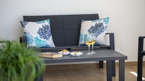 A dark-colored sofa with patterned cushions, a small table with a book, bowls of snacks, and a glass of wine. - Villa Cristal - Sea View Villa With Private Garden (Praiano)