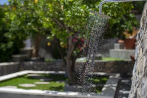 A water feature with a shower head, surrounded by greenery and stone elements.