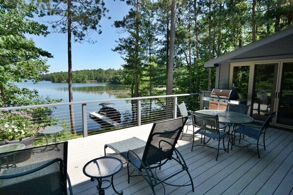 Une terrasse dotée de mobilier d’extérieur, d’un barbecue et offrant une vue sur un lac.