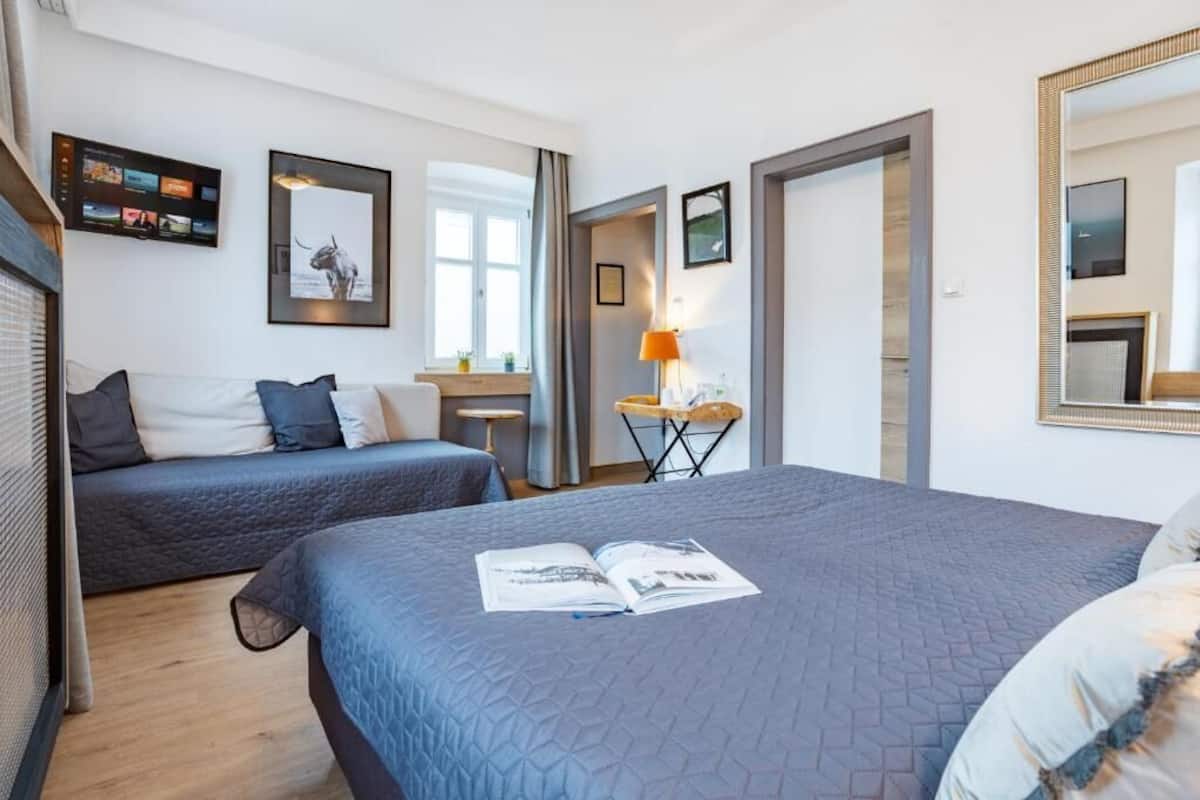 Ein Hotelzimmer mit zwei Betten, einem Schreibtisch, einem Stuhl und einem an der Wand befestigten Fernseher.