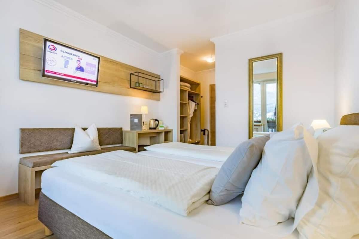 Ein Hotelzimmer mit Bett, Schreibtisch, Wandfernseher, Spiegel und Kleiderschrank.