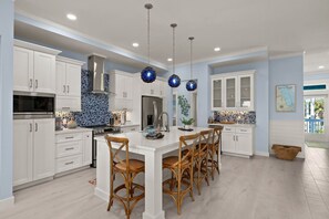 Une cuisine moderne avec des meubles blancs, un îlot central et des globes décoratifs bleus.