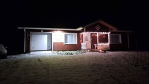 A house with a garage, a porch with string lights, and a small front yard. - Sun's Tupa - Traveller's Marmalade (Siikalatva)