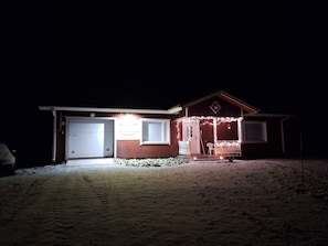A house with a garage, a porch with string lights, and a small front yard.