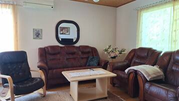 Una sala de estar con un sofá de cuero marrón, una mesa de centro de madera y un sillón negro.