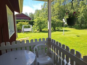 A covered patio with a white fence, a table, and a chair.