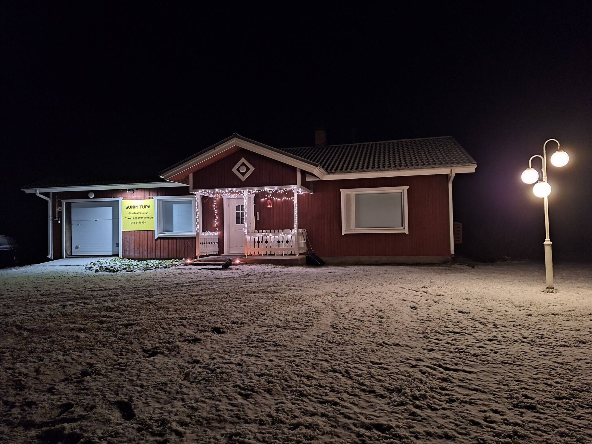 Un edificio pequeño con una puerta blanca y un letrero, rodeado de nieve.