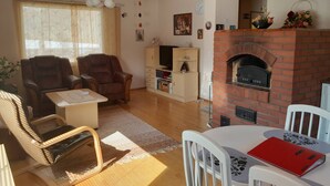 A living room with a fireplace, leather chairs, a television, and a bookshelf. - Sun's Tupa - Traveller's Marmalade (Siikalatva)