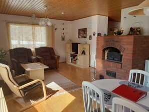 A living room with a fireplace, leather chairs, a television, and a bookshelf.