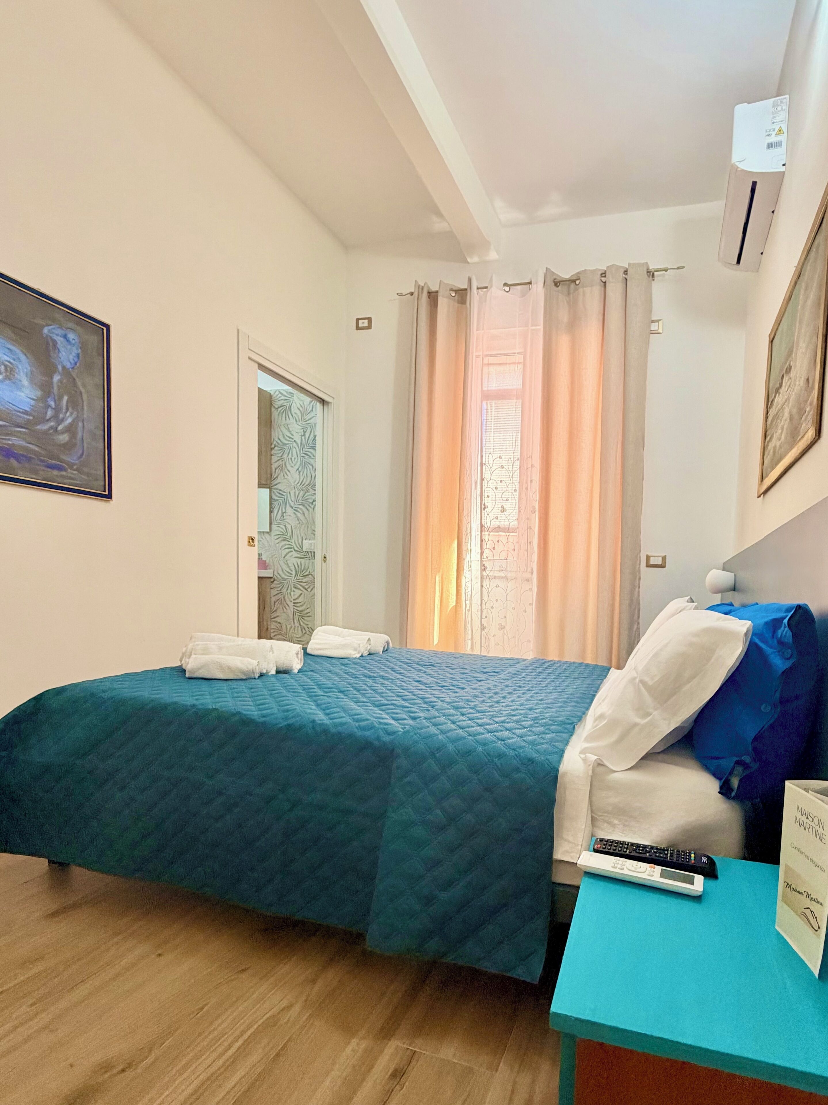 Une chambre d’hôtel équipée d’un lit, d’une table de chevet, d’une télécommande et d’une pancarte indiquant le type de chambre.