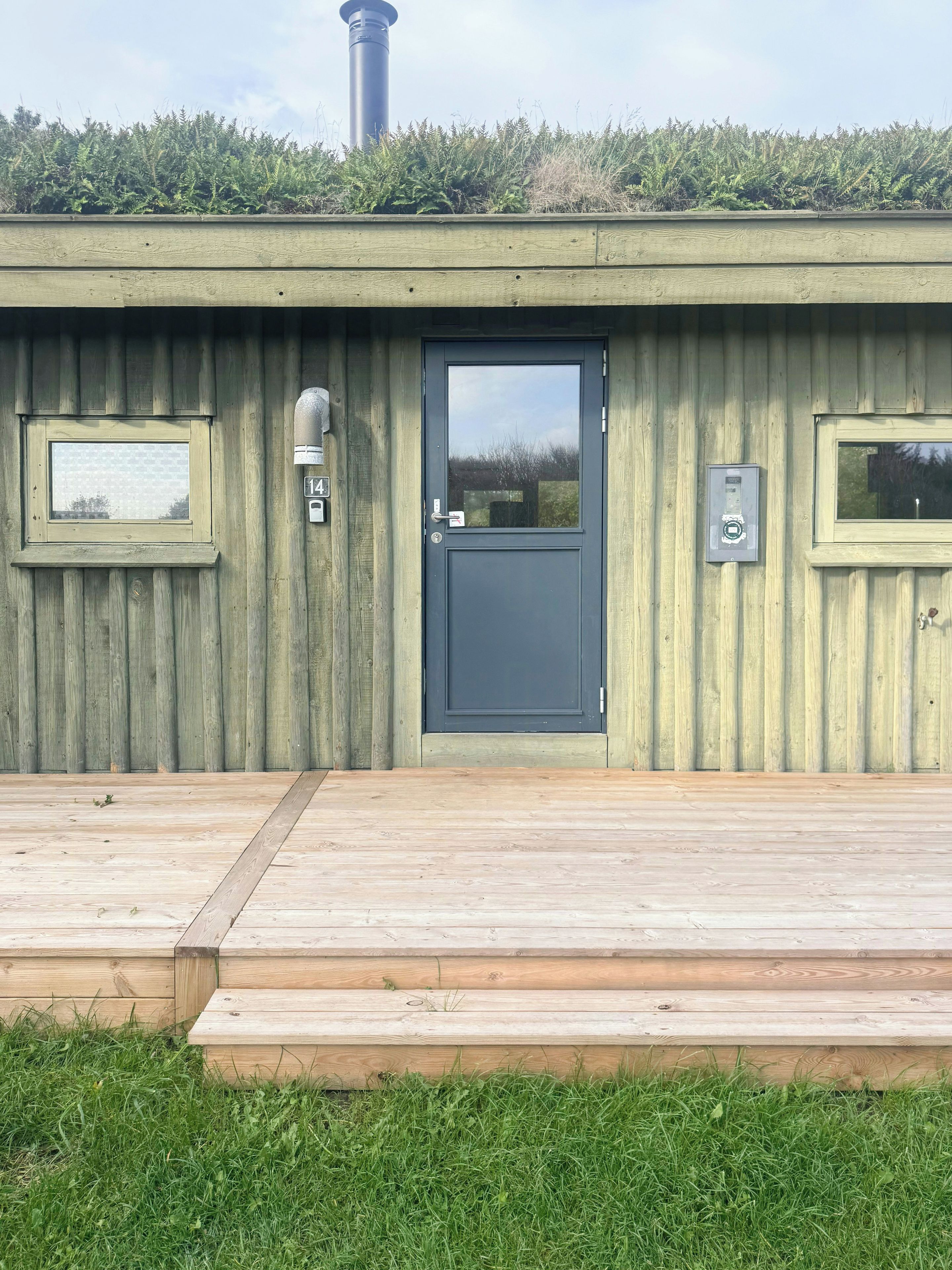 A wooden building with a dark door, two windows, and a small mailbox.