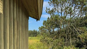 A wooden deck with two striped lounge chairs and a small table, overlooking a grassy area with trees. - House in Kettrup Bjerge near nature and the sea (Kettrup Bjerge)