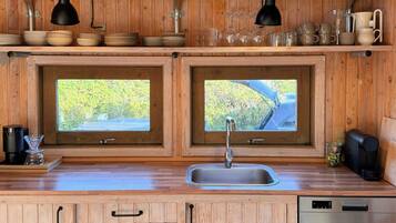 Une cuisine en bois avec deux fenêtres, un évier et un lave-vaisselle.