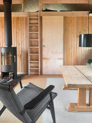 A wooden interior with a fireplace, a table, and a chair. - House in Kettrup Bjerge near nature and the sea (Kettrup Bjerge)