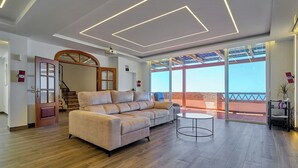 Una sala de estar moderna con un sofá, una mesa redonda y un ventanal con vistas.