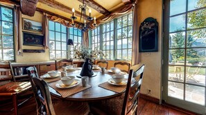 Zona pranzo con tavolo rotondo apparecchiato per sei, circondato da sedie in legno.