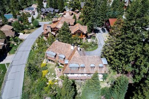 Vista aerea di una zona residenziale con diverse case, tra cui una casa principale con un tetto ampio e vegetazione circostante.