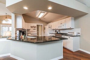 Una cocina moderna con armarios blancos, encimera de granito y una isla central.