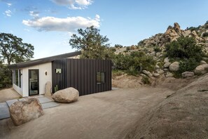 Um edifício moderno com fachada preta, entrada por porta de vidro e calçada pavimentada.
