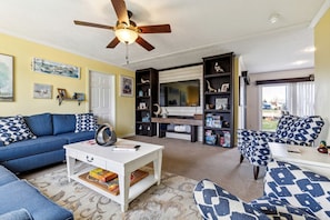 A living room with a sofa, armchair, coffee table, and bookshelf.