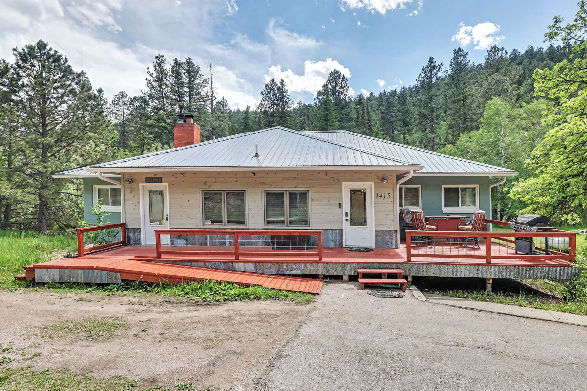 A rustic cabin with a porch, a chimney, and a deck with outdoor seating.