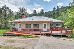 A rustic cabin with a porch, a chimney, and a deck with outdoor seating. - The Hill View Suite at Ten Stone Lodge (Keystone)