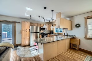 Una cocina moderna con una isla central, electrodomésticos de acero inoxidable y una lámpara colgante.