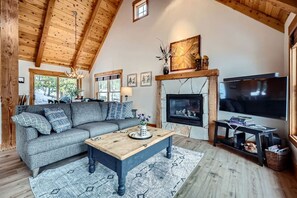 A cozy living room with a fireplace, a sofa, a coffee table, and a TV.