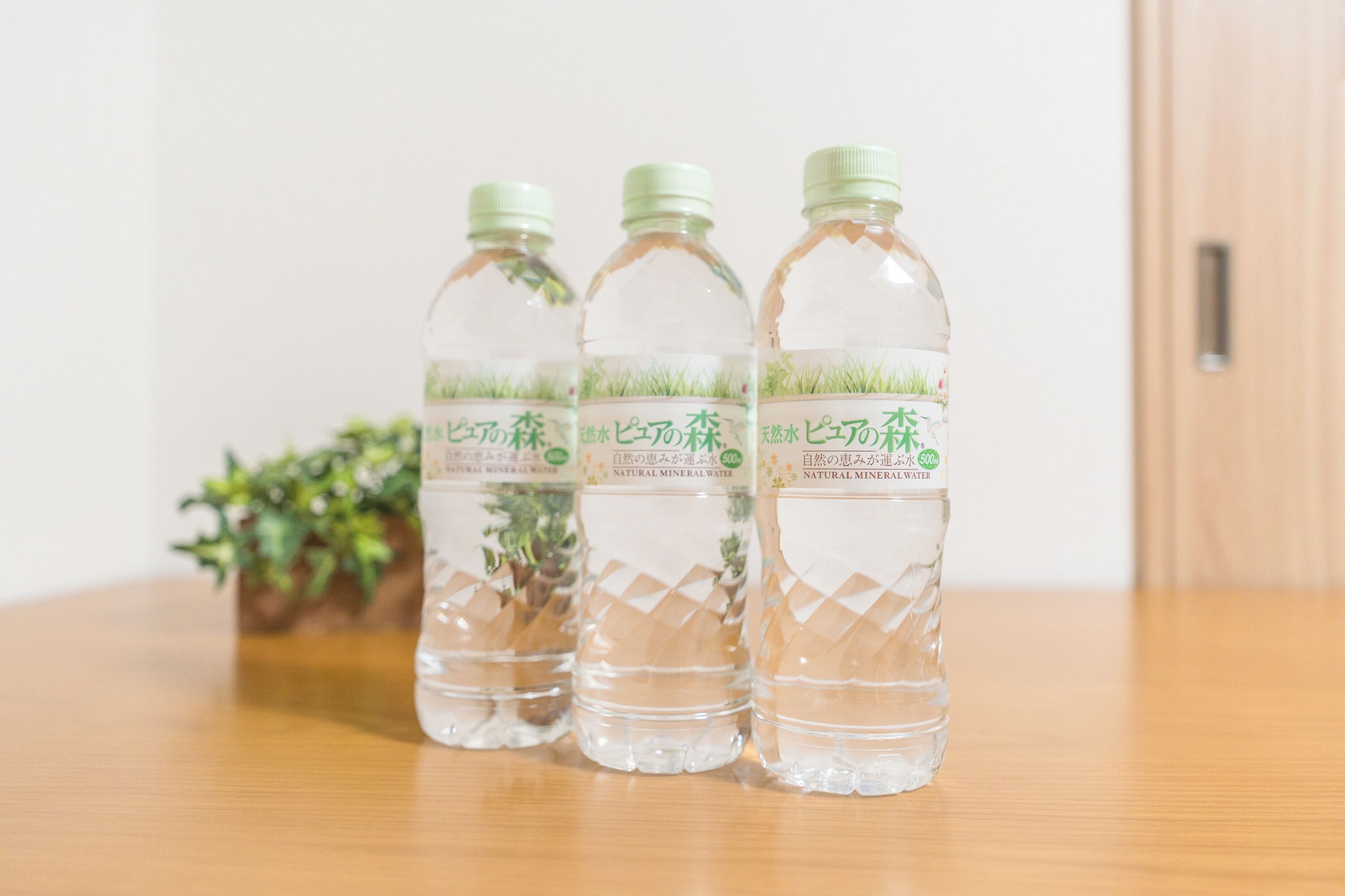 Tres botellas de agua con etiquetas sobre una mesa de madera.