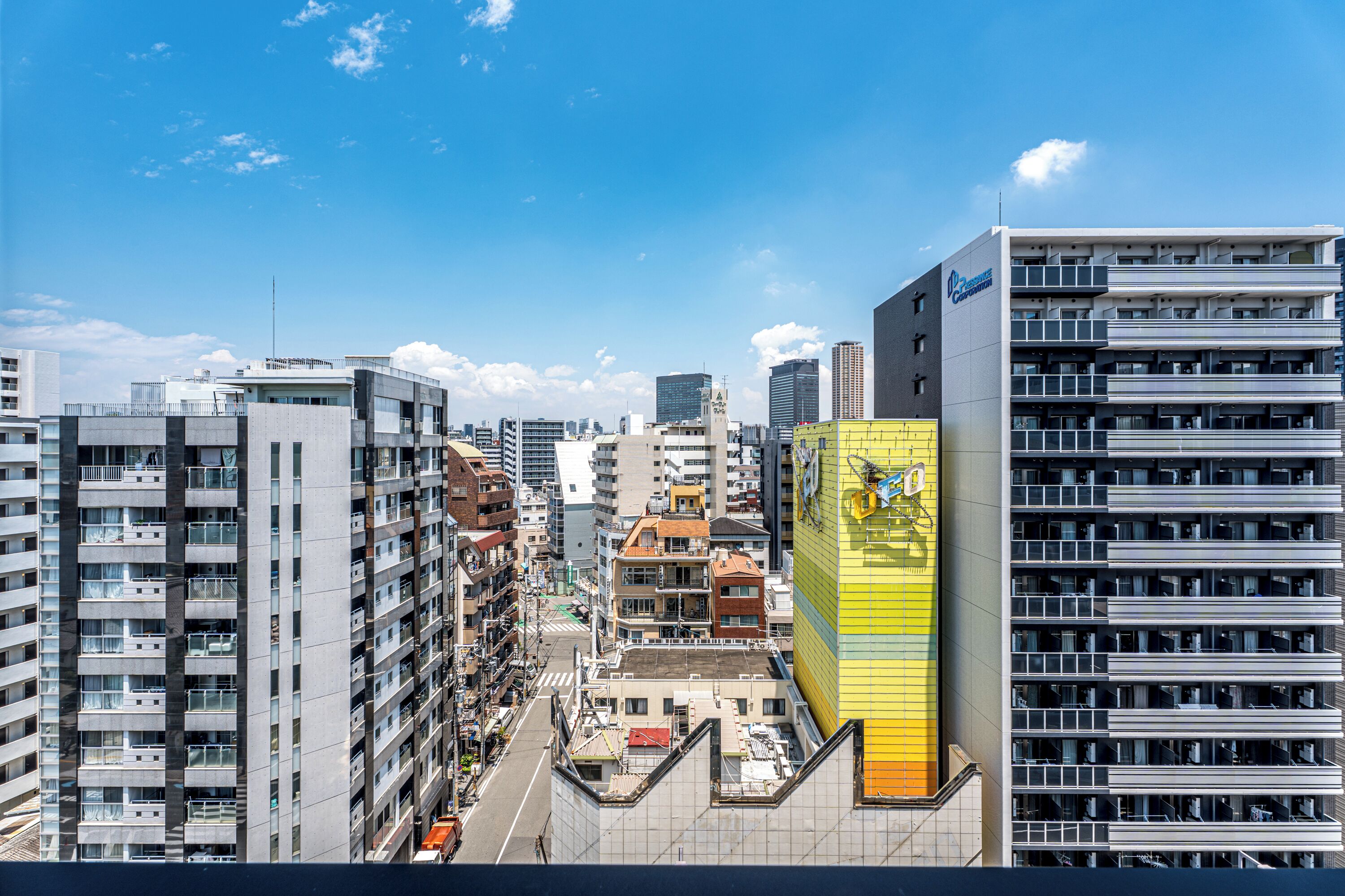 A high-rise building with multiple floors, a prominent yellow facade, and a clear sky.