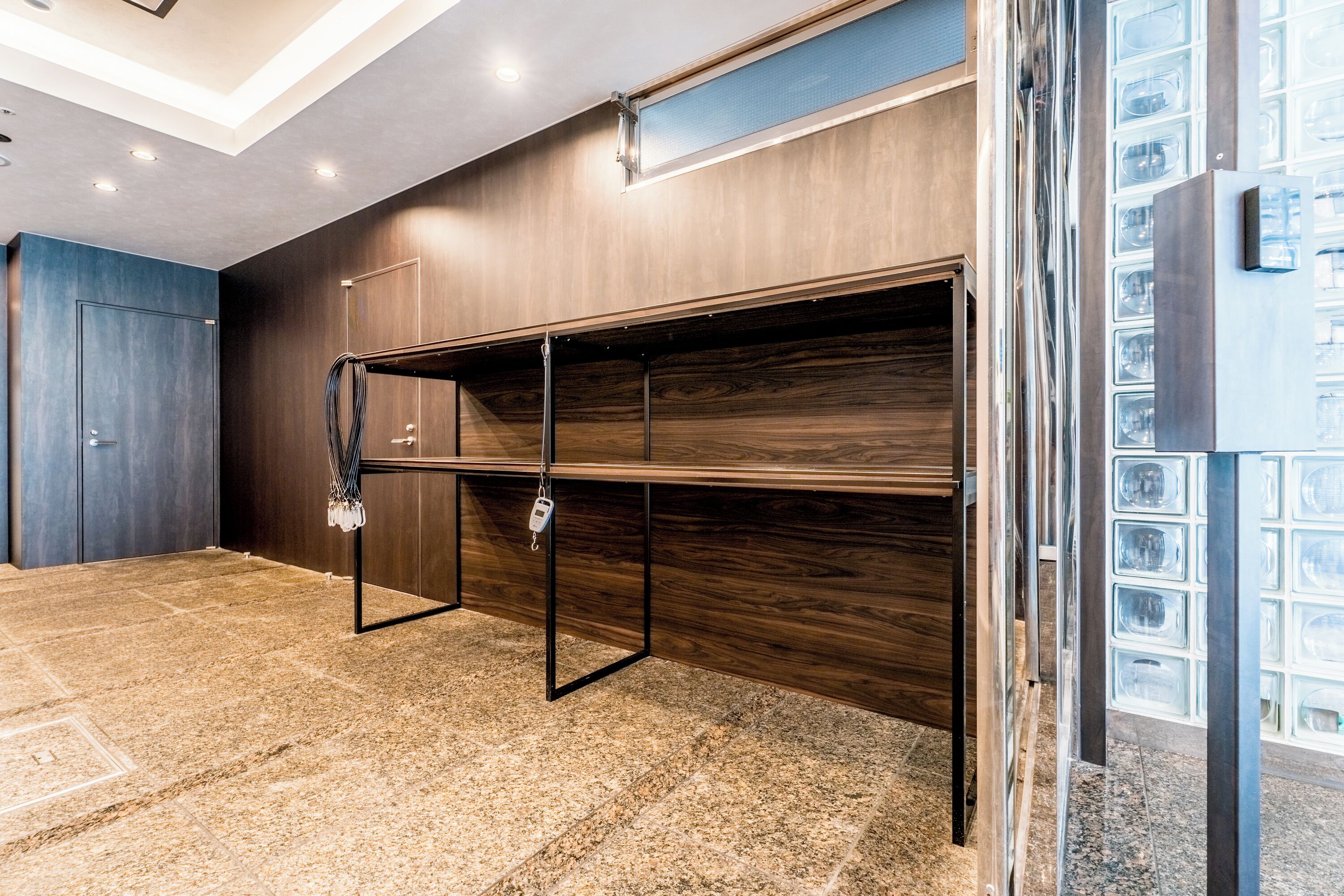 A room with a wooden wall, a metal rack, and a tiled floor.