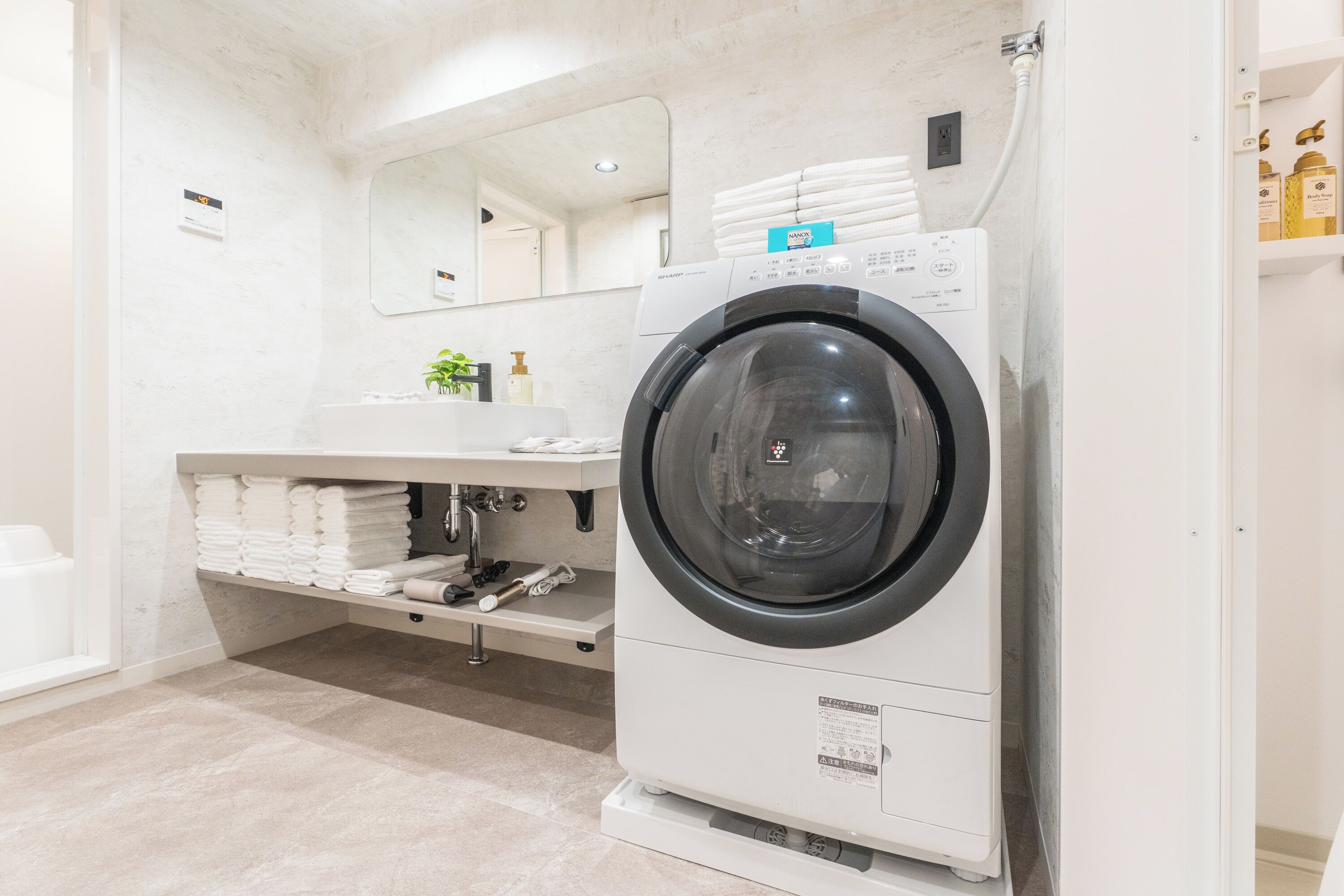 A modern bathroom with a built-in washer and dryer, a sink, and a mirror.