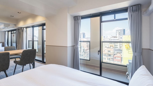 A hotel room with a bed, a dining table with chairs, and a large window with curtains. - Eslead Hotel Namba Daikokucho Annex (Daikoku, Naniwa-ku, Osaka-shi)