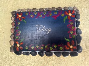 Een decoratieve muur met een bloemistisch schilderij als rand en het woord 'Chay' in het midden.