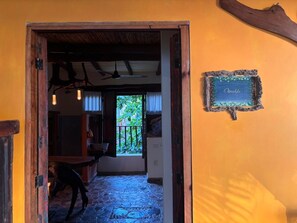 A doorway leading to a room with a stone floor, a wooden table, and a window with a view of greenery. - Habitación Osvaldo (Segundo piso) (San Francisco)