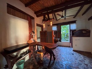 Una cocina rústica con suelo de piedra, vigas de madera y un diseño de mesa de madera único.