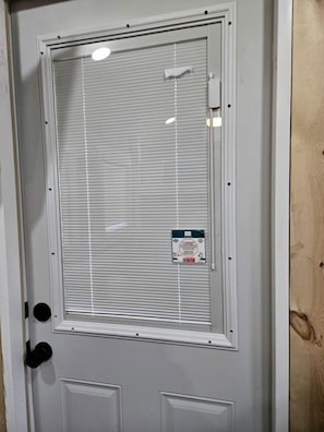 A door with a window, a doorbell, and a small sign on the window. - Rustic Log Cabin with Outdoor Fire Pit and Porch in Toronto, Kansas (Toronto)