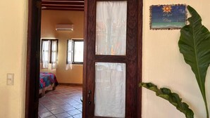 A doorway leading to a room with a bed, a window, and a wall-mounted sign. - Habitación Papa Chuy (Segundo piso) (San Francisco)